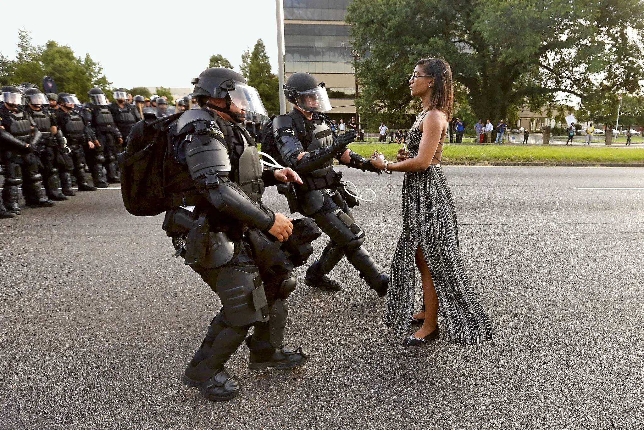 calm, still woman standing in front of two police officers in full riot gear in Baton Rouge, Lousiana. 