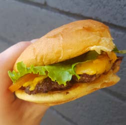 A cheeseburger is held in a close-up shot